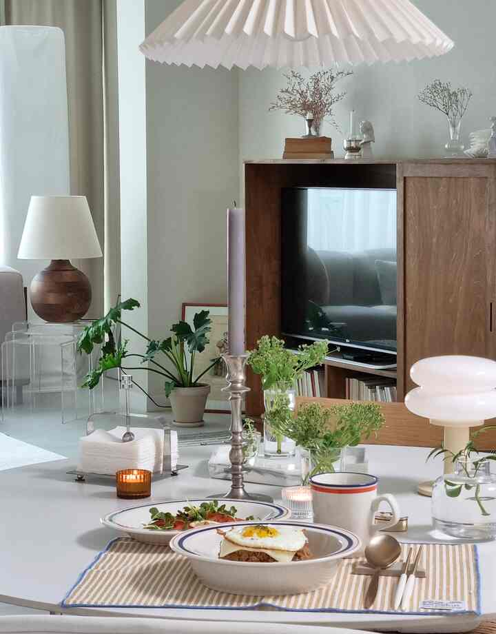 Natural and white wood tone living room with central dining table set for brunch, creating a warm and inviting atmosphere