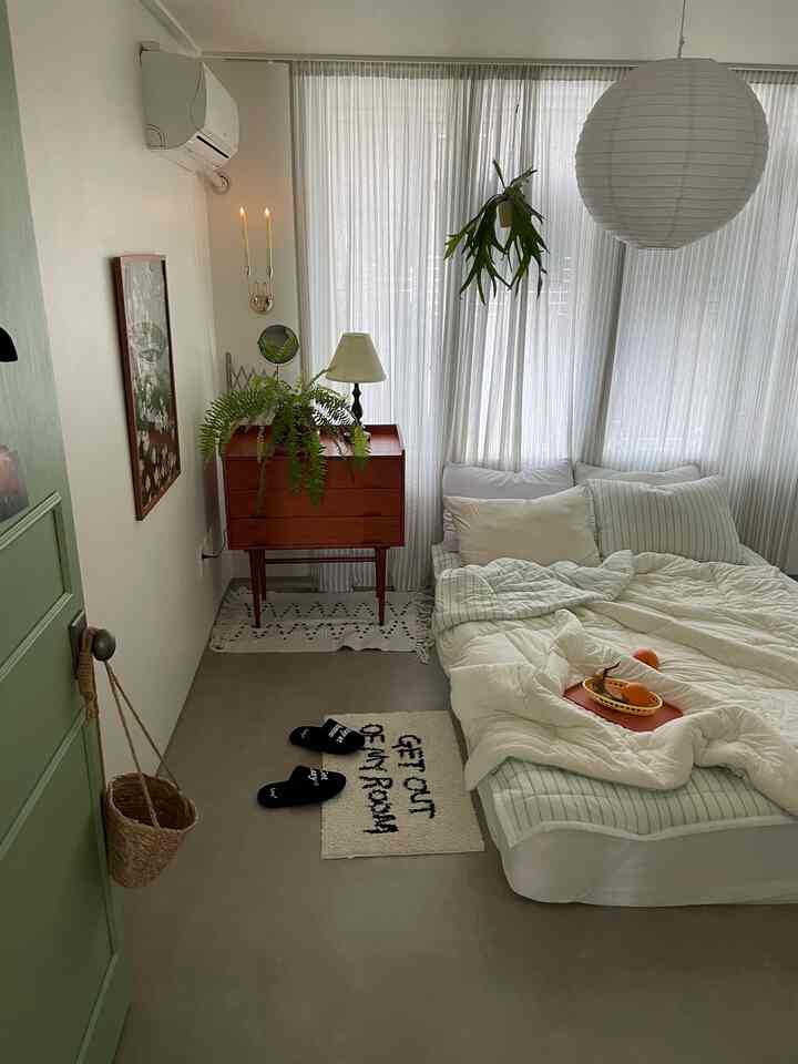 ホワイトとベージュのトーンの寝室、ヴィンテージコンソールと植物が配置された明るく居心地の良い空間