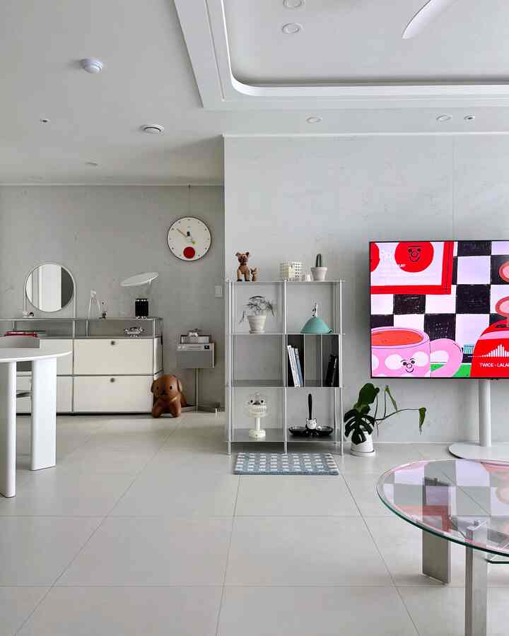 白を基調としたリビング、整った棚とテレビ台が配置され、多彩なオブジェが飾られたモダンな空間