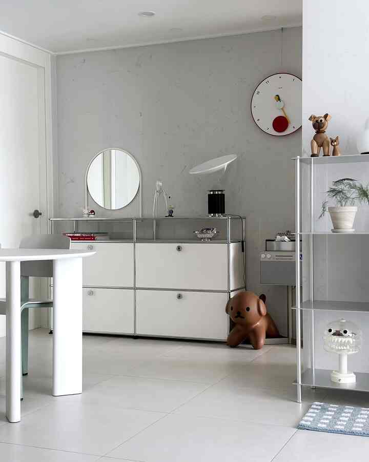 A minimalistic living room in white and silver tones featuring sleek storage cabinets and modern decor in a clean setting