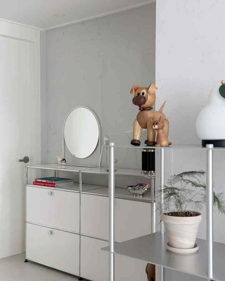 Modern living room with light gray walls and silver metal storage units, featuring a plant and animal-shaped decorations