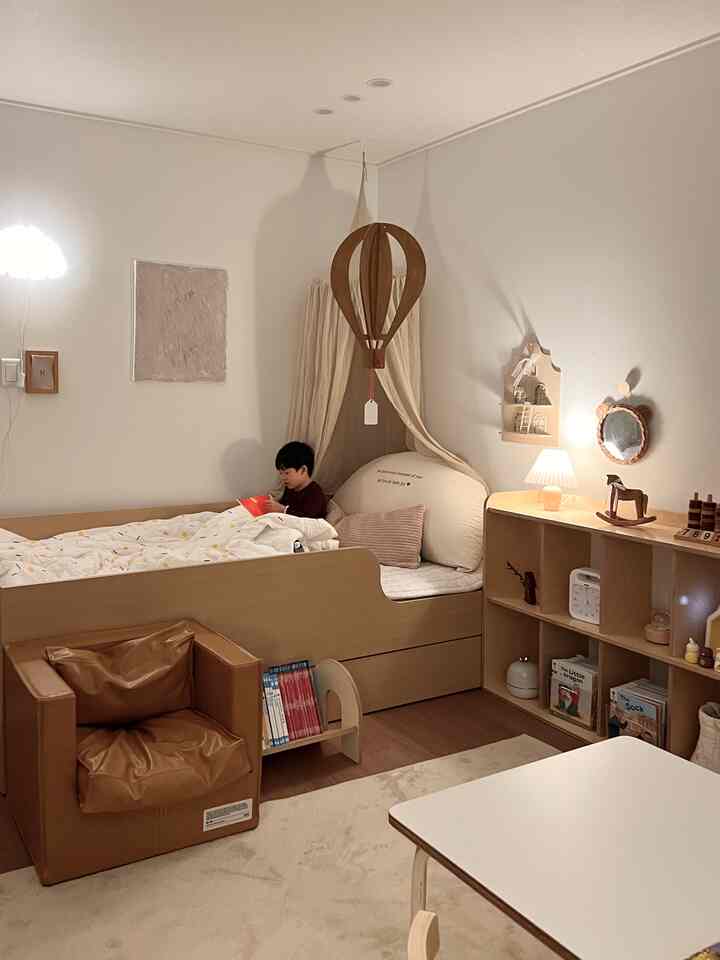 暖かみのある木目調と白が調和した子供部屋、キャノピー付きのキッズベッドと本を読む子供がいる落ち着いた空間