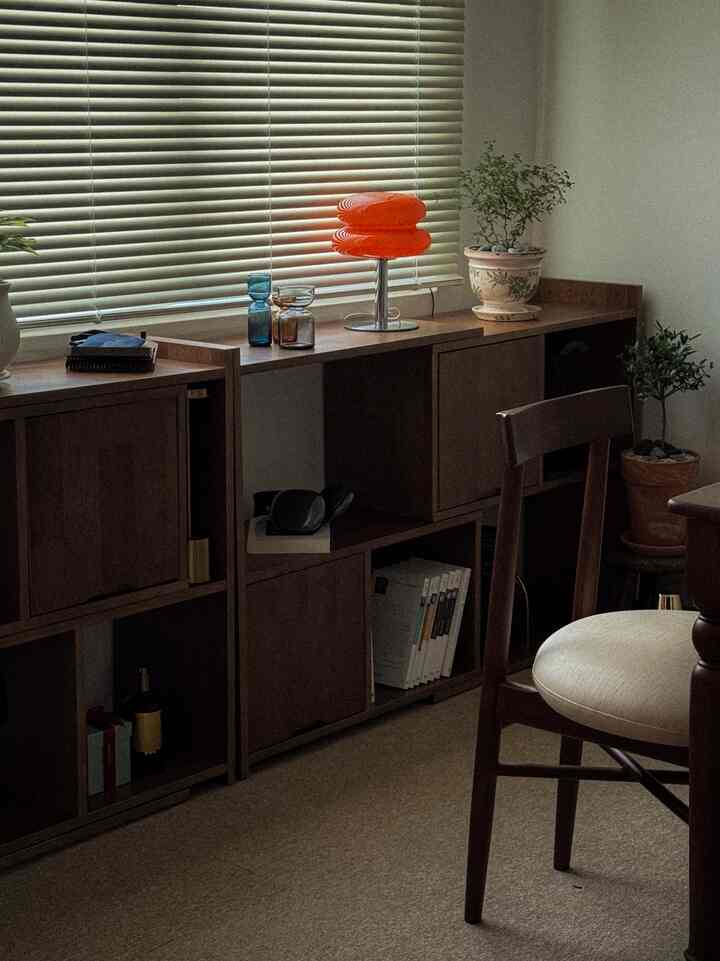 A calm and antique dining room interior featuring light beige flooring, walnut wood furniture, and a round stool