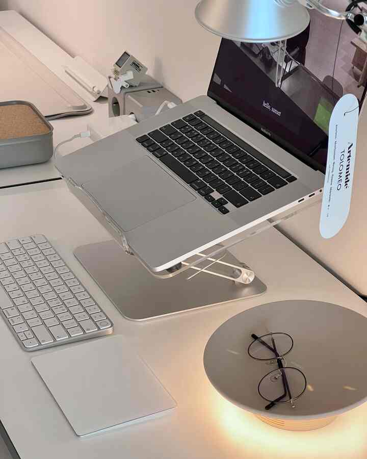 A tidy home office space on a white desk featuring a silver laptop and keyboard