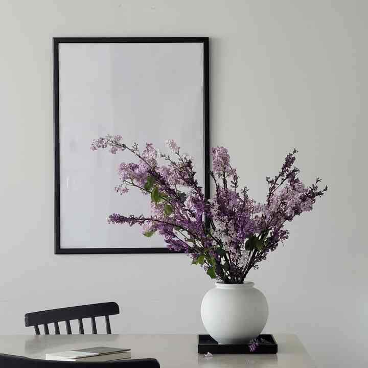 White and black toned dining room featuring a vase with purple flowers and a simple framed artwork