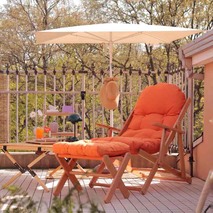 Beige parasol and orange cushioned folding armchair on wood tone terrace rooftop space