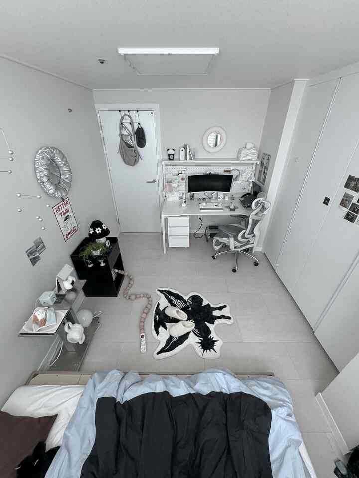 モノトーンとホワイトの色調のコンパクトな寝室、すっきりとしたデスクとチェア、特徴的なラグが配置されたシンプルモダンなインテリア