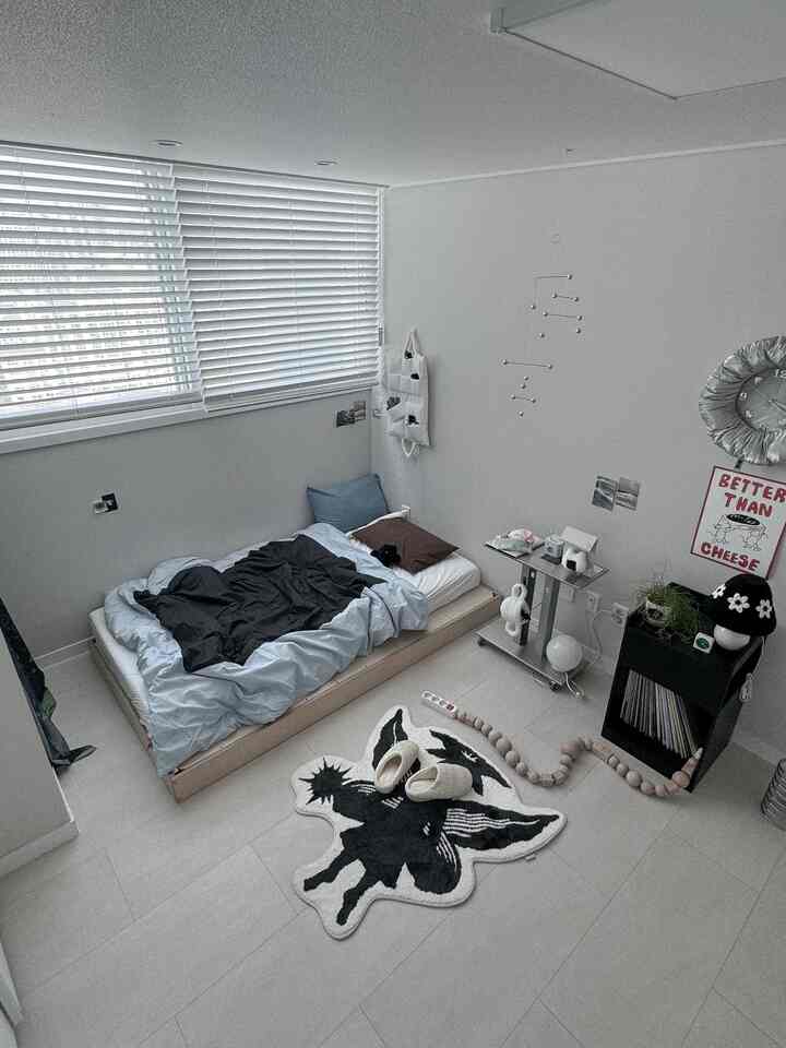 ナチュラルカラーのモダンな寝室、低いベッドとブラインド、壁時計とポスターが配置されたシンプルな空間