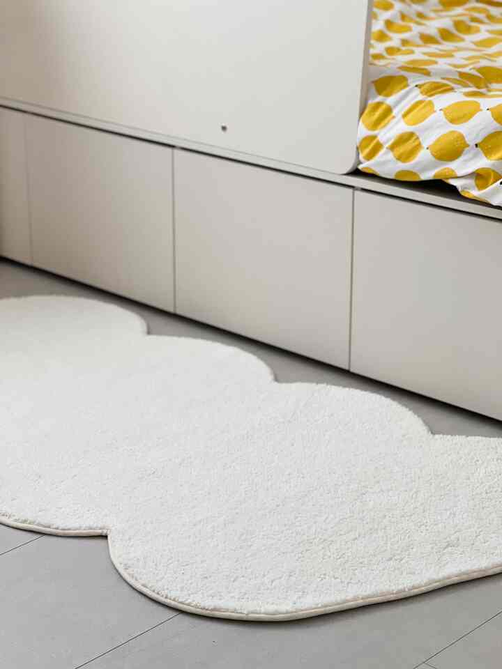 White and yellow toned kids' room featuring a storage drawer bed frame and a cloud-shaped white carpet with cozy atmosphere
