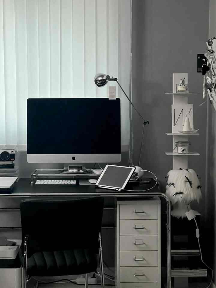 チャコールとホワイトのトーンのワンルームホームオフィス、整理されたデスクとiMac、収納棚が配置されたモダンな空間