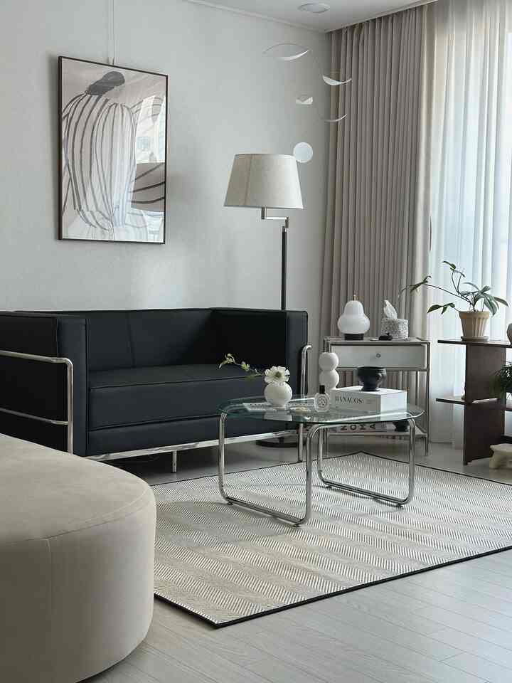 ホワイトとブラックのトーンのモダンなリビングルーム、ブラックレザーのソファとヘリンボーンパターンのラグが配置された空間