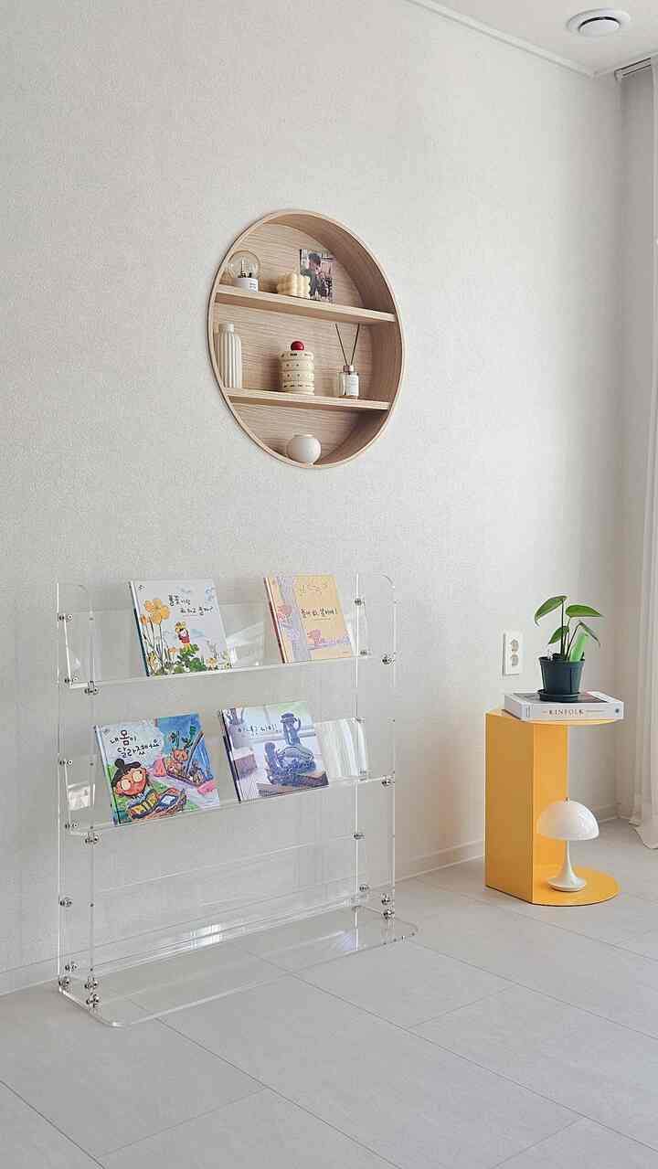 Light gray wall Nordic simple living space featuring transparent acrylic bookshelf and yellow side table with plant