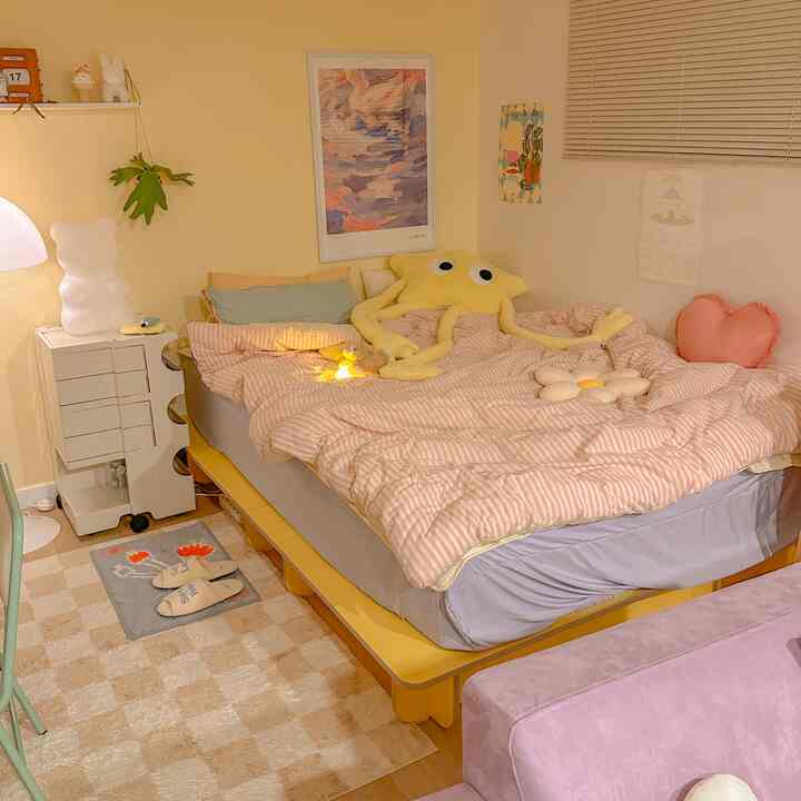 黄色の壁とベッドが配置された落ち着いた寝室、ピンクの寝具とアクセント小物付きのインテリア