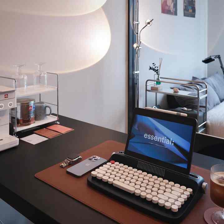 黒と茶色のトーンのホームオフィス、ミッドセンチュリーモダンスタイルのデスクにタブレットとキーボードが配置された整った作業空間