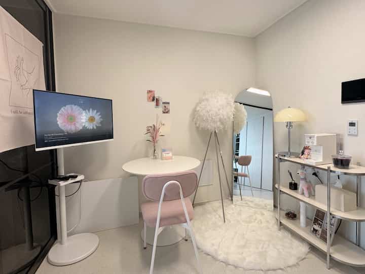 A cozy small living room space in beige and white tones featuring a full-length mirror, round table, and fluffy rug