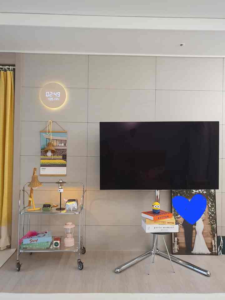 Modern interior with gray wall panels, chrome TV stand and storage cart featuring various décor accessories