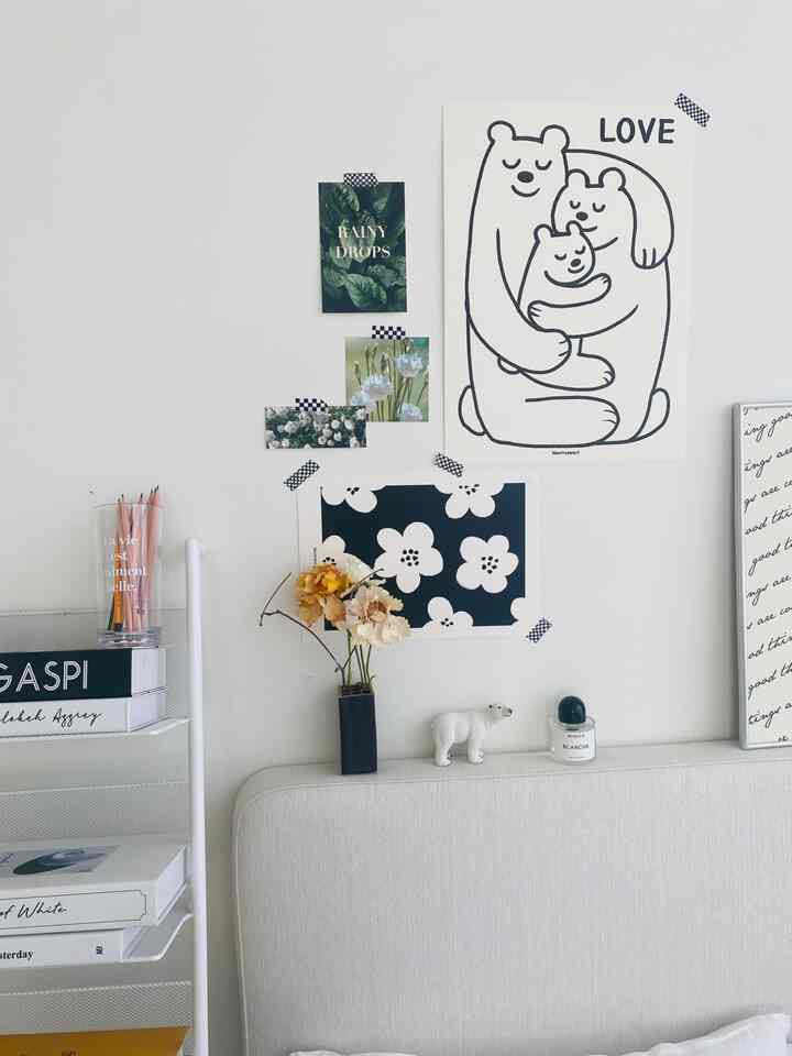 モノトーンの白い壁とベッドのある寝室、壁には黒と白のポスターと花瓶が配置された雰囲気のある家族空間