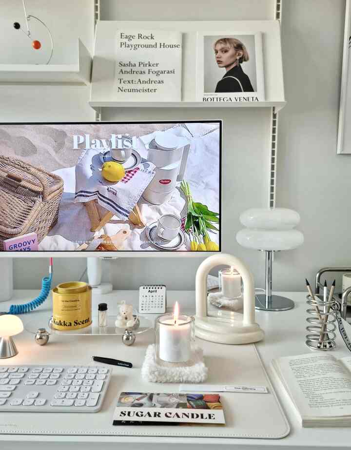 白いトーンのホームオフィス、中心に整頓されたデスクとキャンドル、モダンな照明が配置された雰囲気のあるインテリア