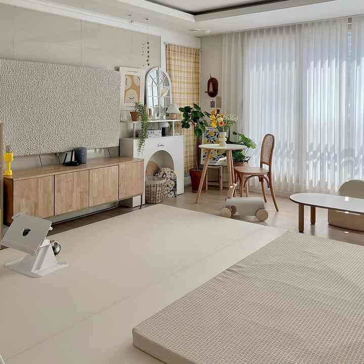 白とウッドトーンが調和した明るく居心地の良い子供部屋、ナチュラルな木製家具と透け感のあるカーテンが配置された雰囲気のあるインテリア