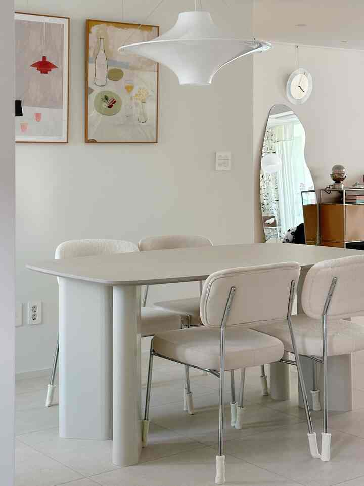 白色調のキッチンとダイニング、6人用ダイニングテーブルと額縁が配置されたシンプルなインテリア