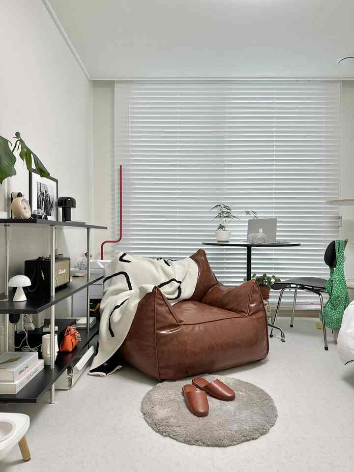 白と茶色のウッドトーンが調和した小さな作業室、ブラウンのビーズクッションソファと丸テーブルが居心地の良い雰囲気を演出