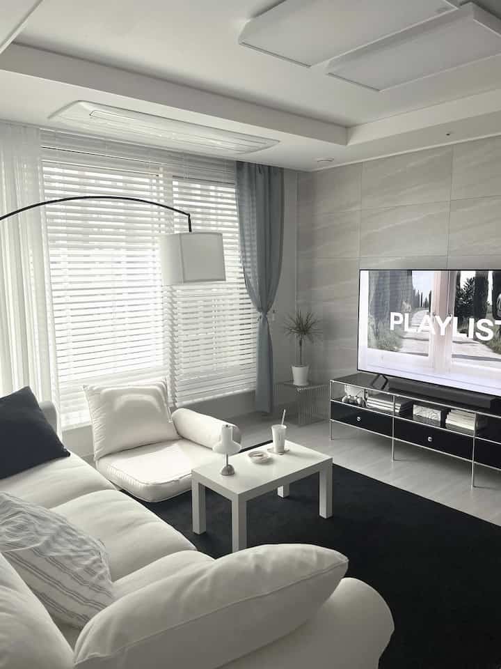 A modern living room in white and black tones featuring a large sofa, coffee table, and TV stand, creating a clean and cozy atmosphere