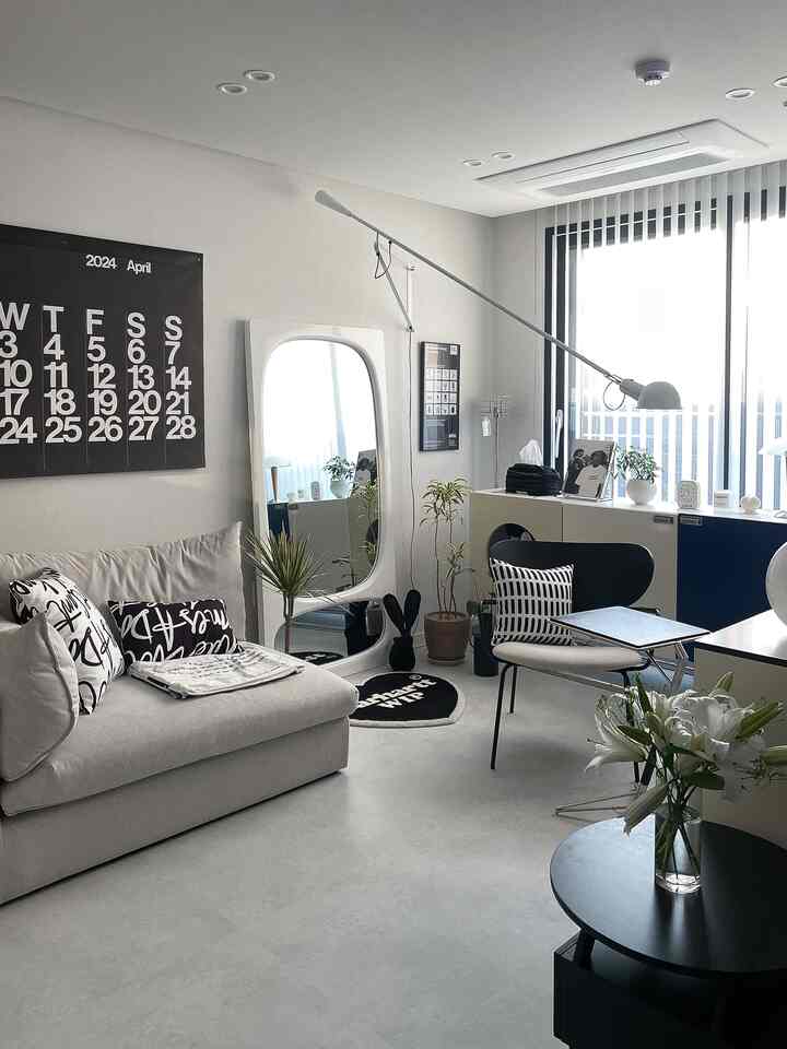 白と黒のモダンなリビングルーム、全身鏡と花瓶、ソファが配置され、清潔感と洗練された雰囲気のあるインテリア