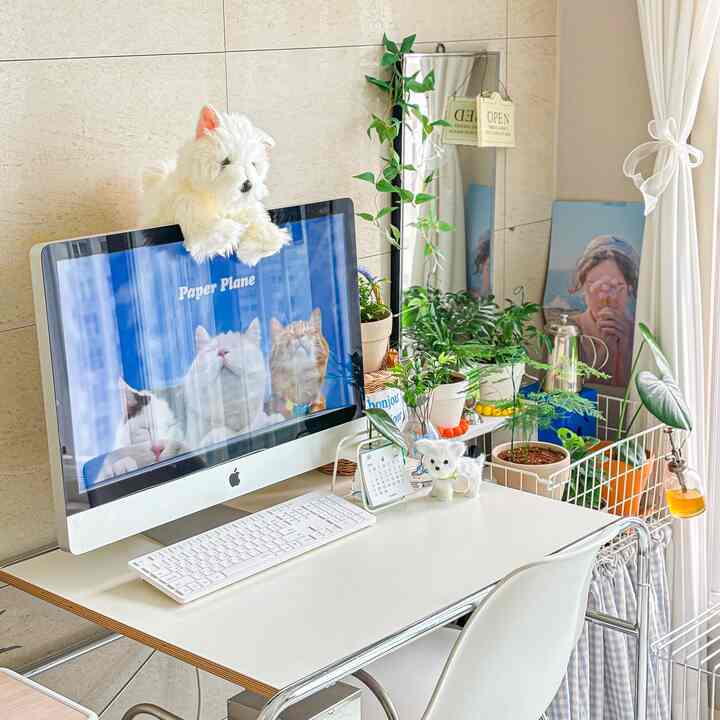 白とナチュラルカラーの調和したホームオフィス、猫のぬいぐるみとパソコンが置かれた雰囲気のある空間