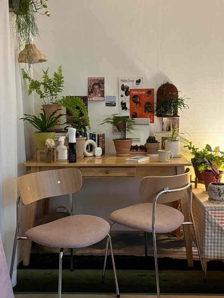 ナチュラルな木目調とベージュ色のホームカフェダイニングルームで、植物とレトロなポスターが調和した雰囲気のある空間