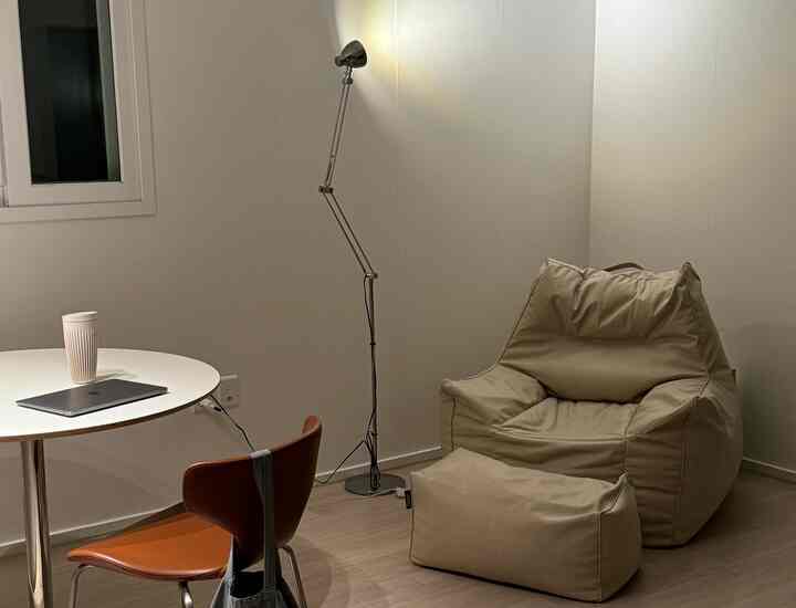 ベージュのビーズクッションと白い円形テーブルがあるシンプルでモダンなリビング空間