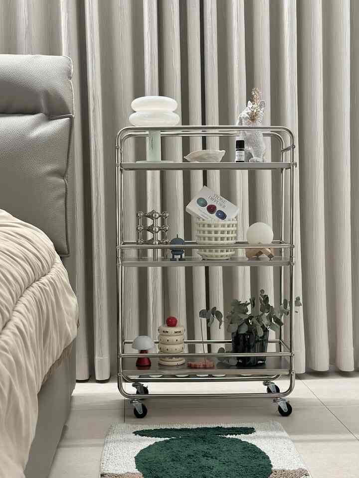 ベージュと白のトーンの寝室、中央にミッドセンチュリーモダンスタイルのステンレストロリーとかわいい小物が配置された雰囲気のあるインテリア