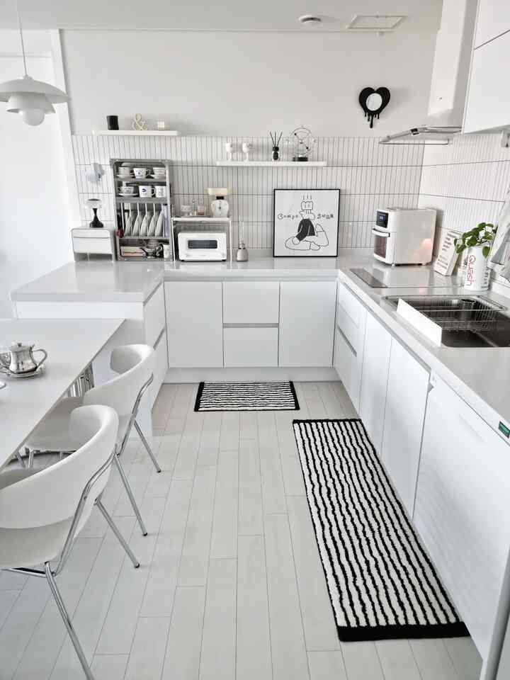 Bright and clean white-toned mid-century modern kitchen featuring black-and-white striped rugs and dining chairs