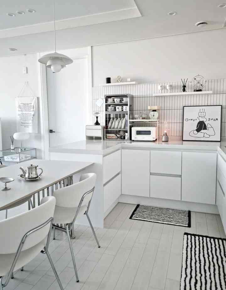 白を基調としたキッチン、ミッドセンチュリーモダンのダイニングテーブルと椅子が配置された印象的な空間