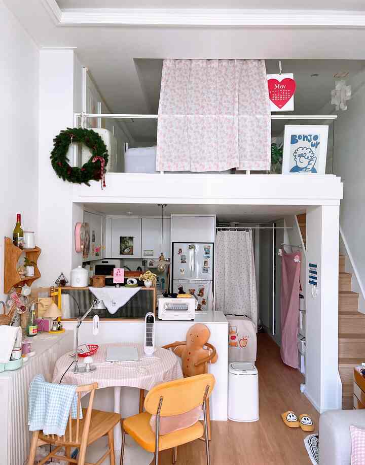 白と木目調のロフト付きワンルーム、ダイニングテーブルと椅子が配置された雰囲気のあるインテリア