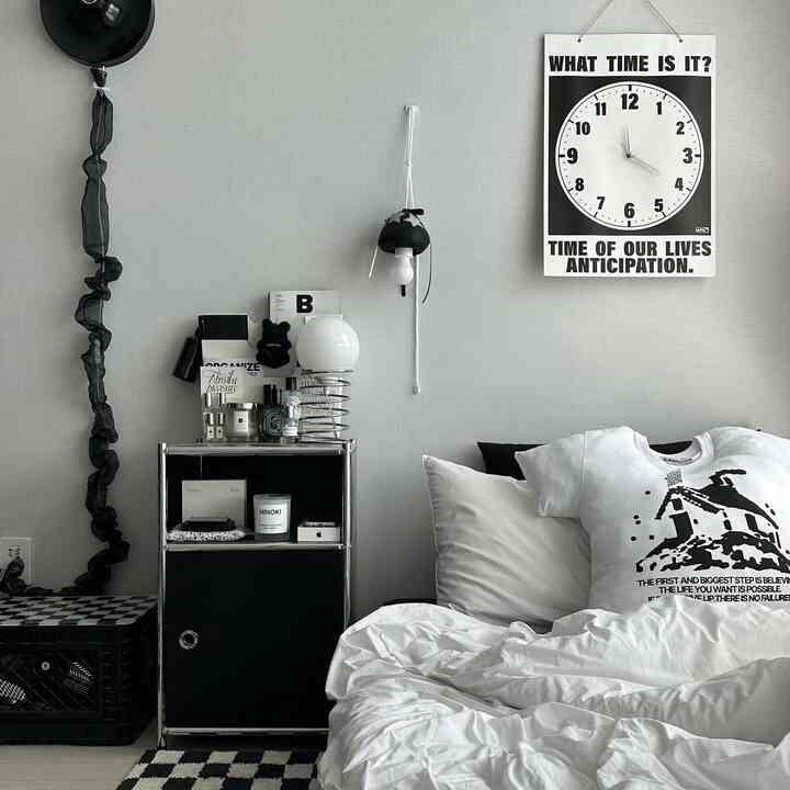 Simple modern bedroom in white and black tones, featuring bed, nightstand, and monotone wall art with clean interior design