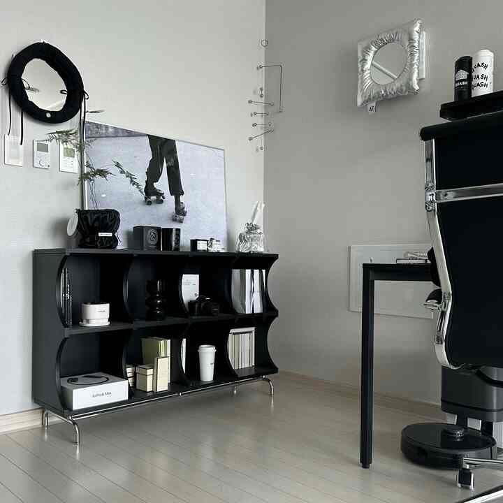 A modern home office space with black furniture against white walls and floor, featuring a clean and sleek atmosphere