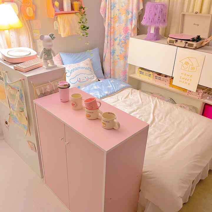 パステルトーンのピンクとブルーが調和するかわいらしい寝室、実用的な収納家具とホームカフェの雰囲気がある空間