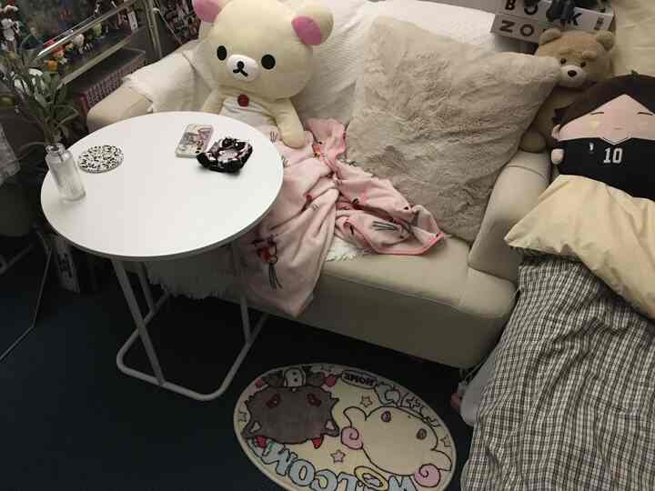 ベージュとホワイトトーンの狭いリビングスペース、キャラクターぬいぐるみとソファ、小さなラウンドテーブルが配置された雰囲気のあるインテリア