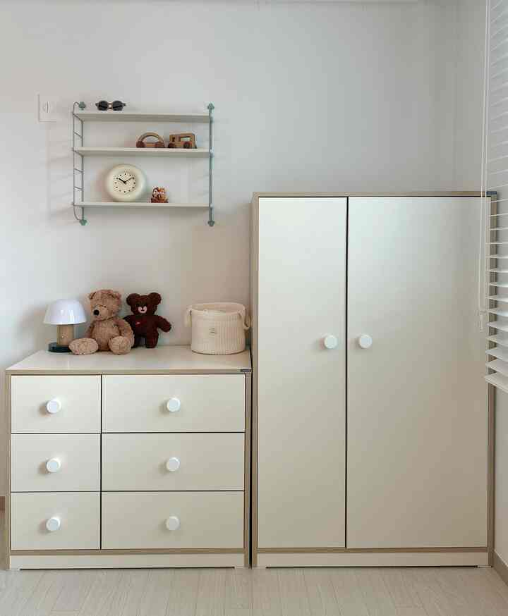 ナチュラルカラーの子供部屋、ベージュのワードローブとチェストにぬいぐるみと棚が配置された清潔感あるインテリア