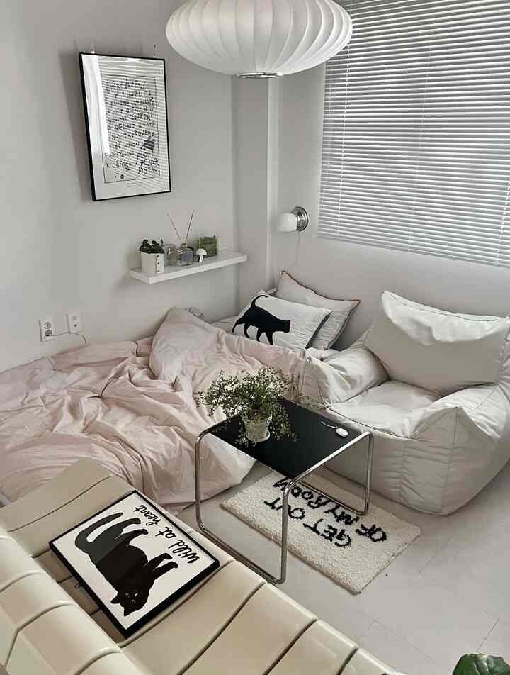 白と黒のトーンが特徴的な一人暮らしのリビング、ビーズクッションソファとラグ、植物が配置された雰囲気のある空間