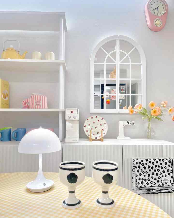 Bright white and yellow-toned kitchen space featuring floral wine glasses and a checkered tablecloth, creating a cozy atmosphere