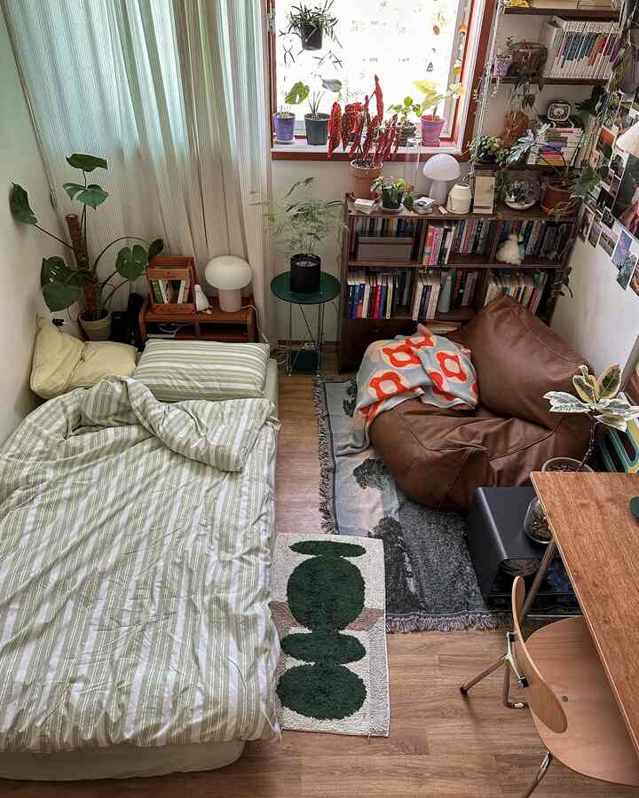 ナチュラルな木目調と植物が調和した小さな寝室、ビーズクッションソファと本棚が落ち着いた雰囲気のインテリア