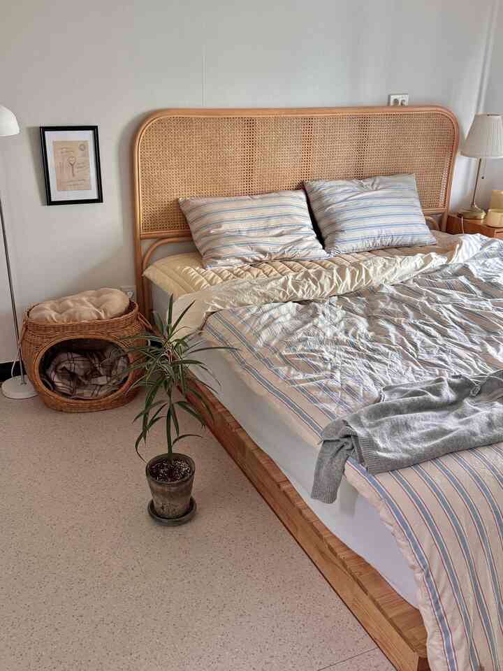 ナチュラルなベージュ調の寝室、ラタンのベッドフレームとペット用ラタンハウスが配置された落ち着いた空間