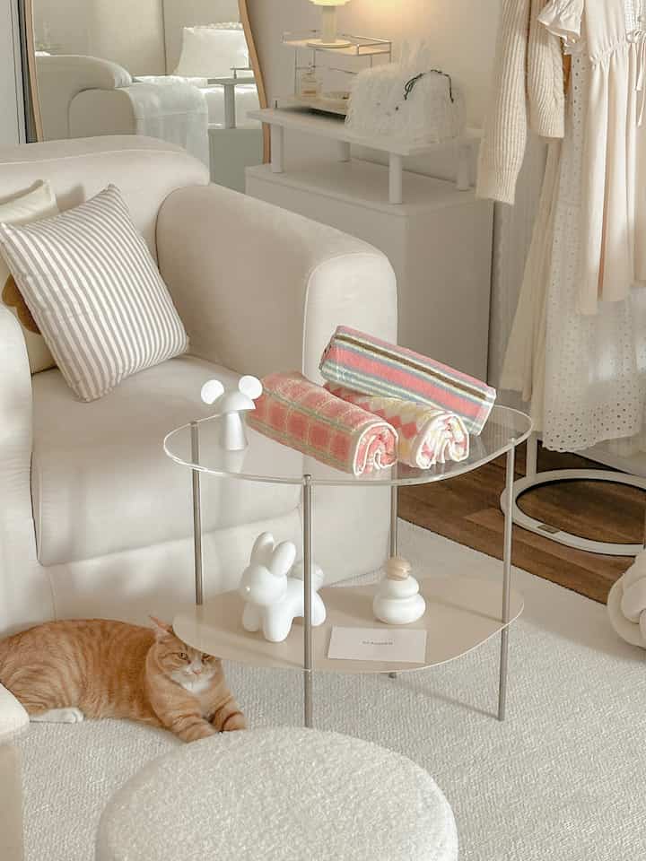 Cream white toned living room featuring sofa, stool, and a relaxed cat in a natural atmosphere