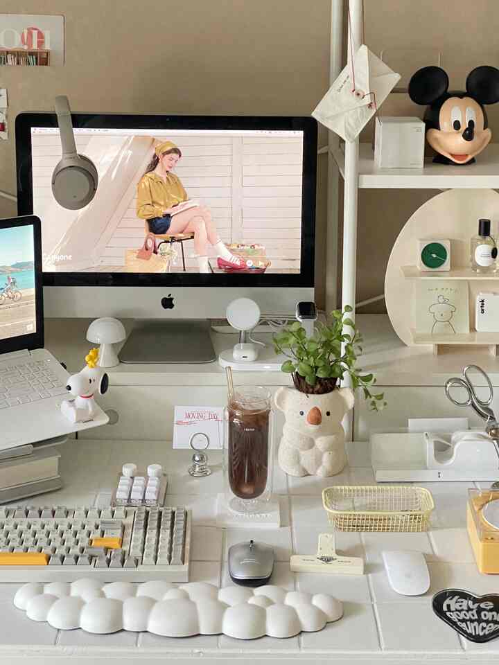 Natural color and white toned home office desk featuring monitor, iced coffee, and Mickey Mouse figure in tidy setting