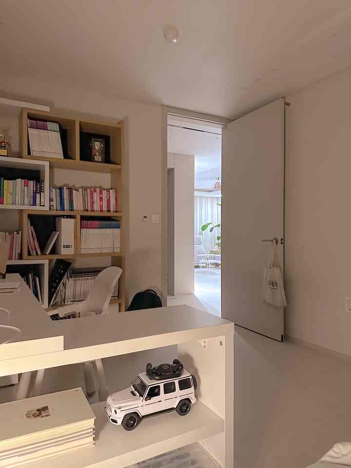 White-toned study space featuring a desk and bookshelf with a minimal, compact atmosphere