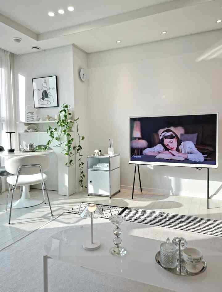 明るいホワイトトーンのリビング、モダンなインテリアとテーブル、テレビ台、植物が配置された印象的な空間