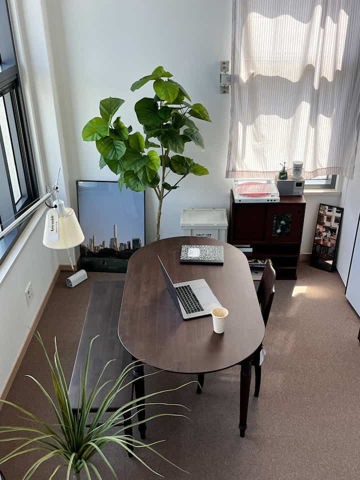 Natural wood-tone dining room with a wooden dining table and chair, bright curtains and plants create a modern atmosphere