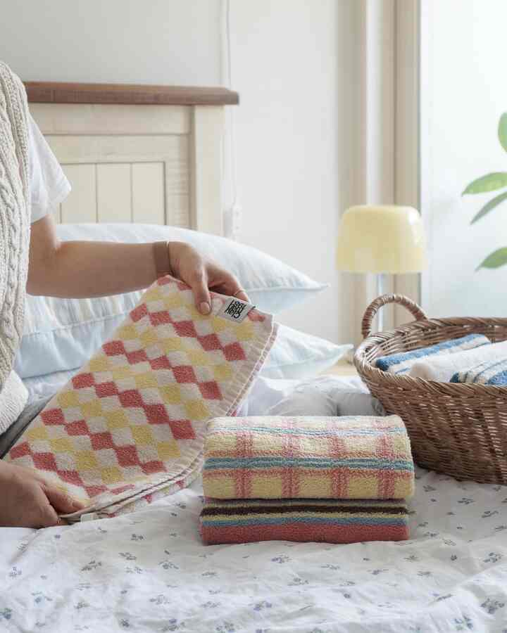 Bright cozy bedroom featuring soft beige and pink towels neatly arranged on bed