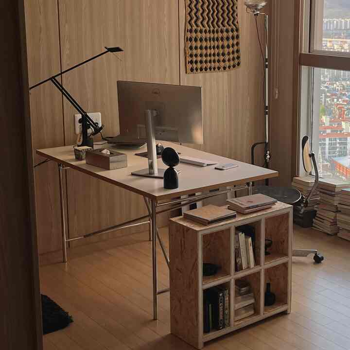 ナチュラルな木目調の壁と床があるホームオフィス、シンプルなデスクとオフィスチェア、収納棚が配置されたミニマルな雰囲気のインテリア